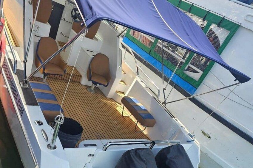 A boat deck with seating, a canopy, and a wooden floor. 4
