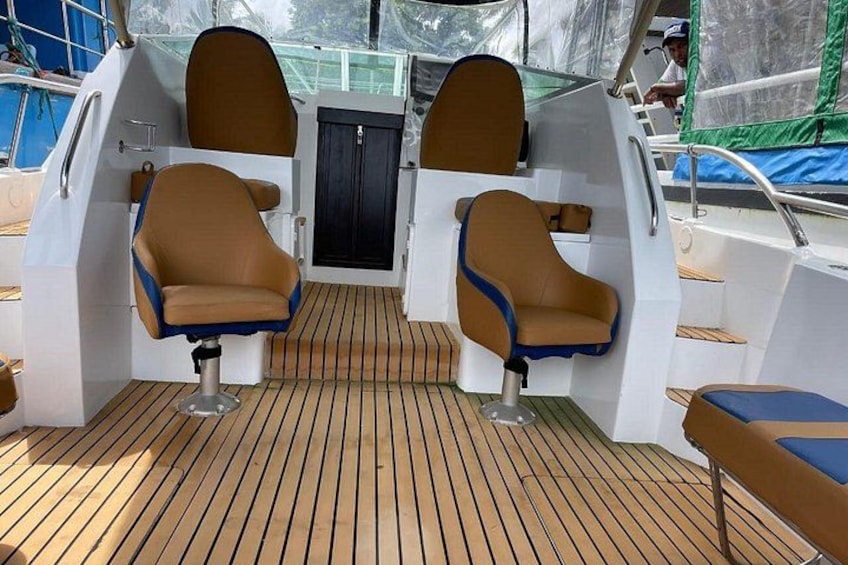 A boat deck with two cushioned seats, a small table, and a wooden floor. 2