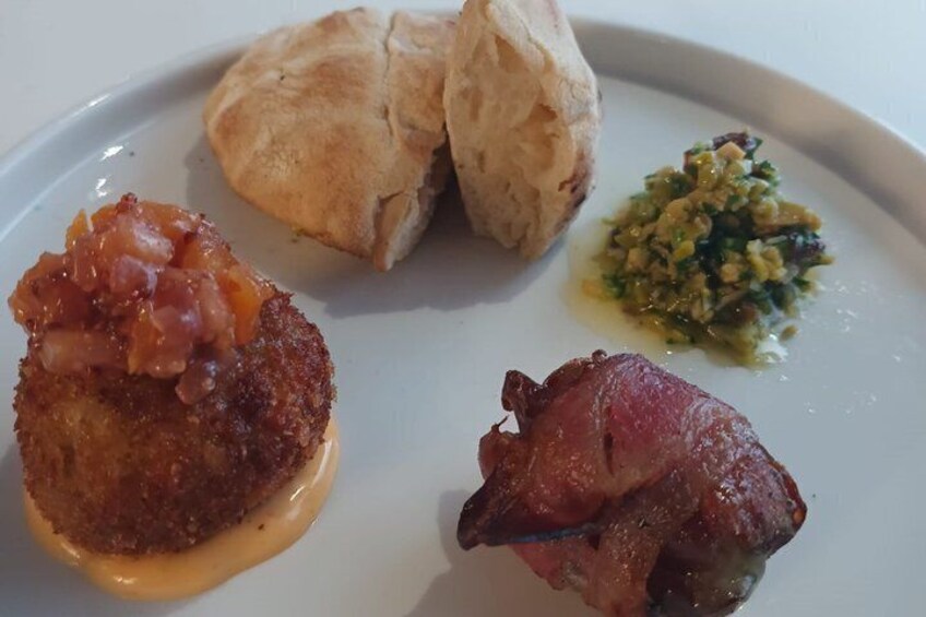 En tallrik med något panerat och friterat, en bit kött och en grön sås. 2