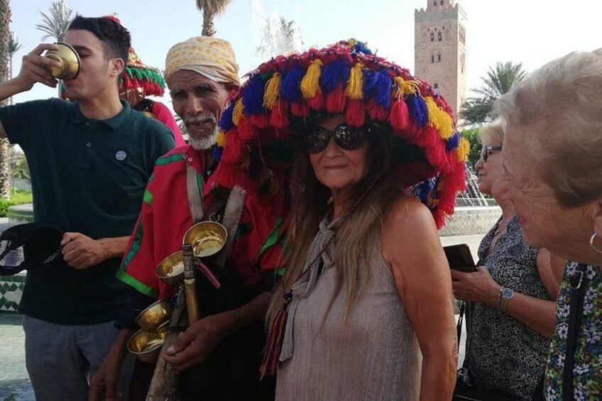 A group of people outdoors, some holding drinks, with a tower and palm trees in the background. 1