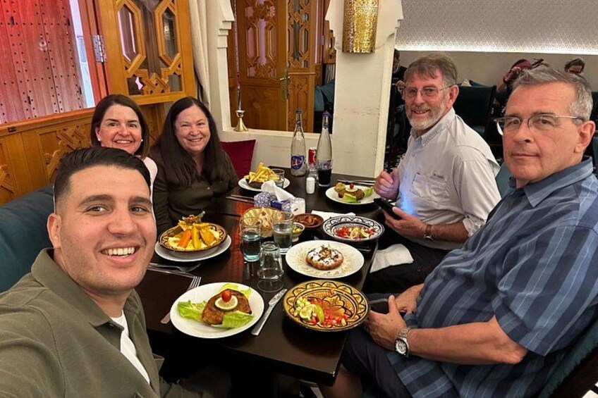 A group of people seated around a table with various dishes. 5