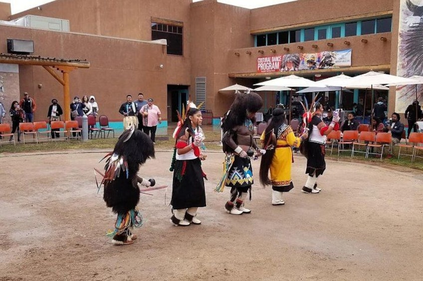A cultural dance performance in an outdoor setting with a building in the background. 2