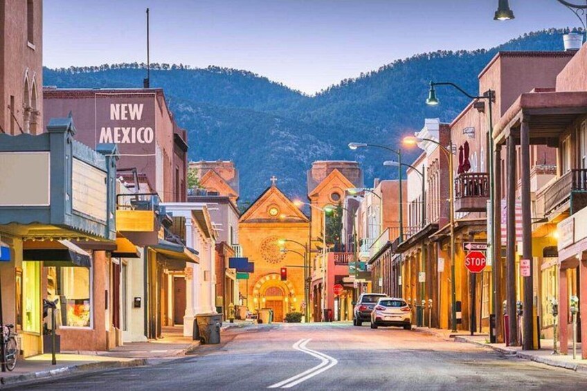 A street in New Mexico with buildings, a church, and a mountain in the background. 2