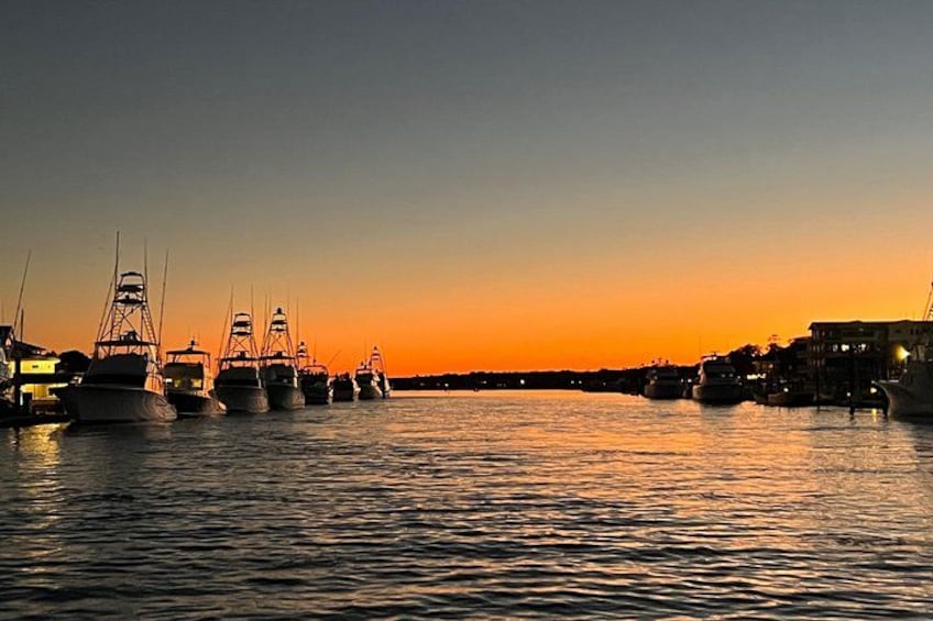 A marina at sunset with several sailboats docked. 5