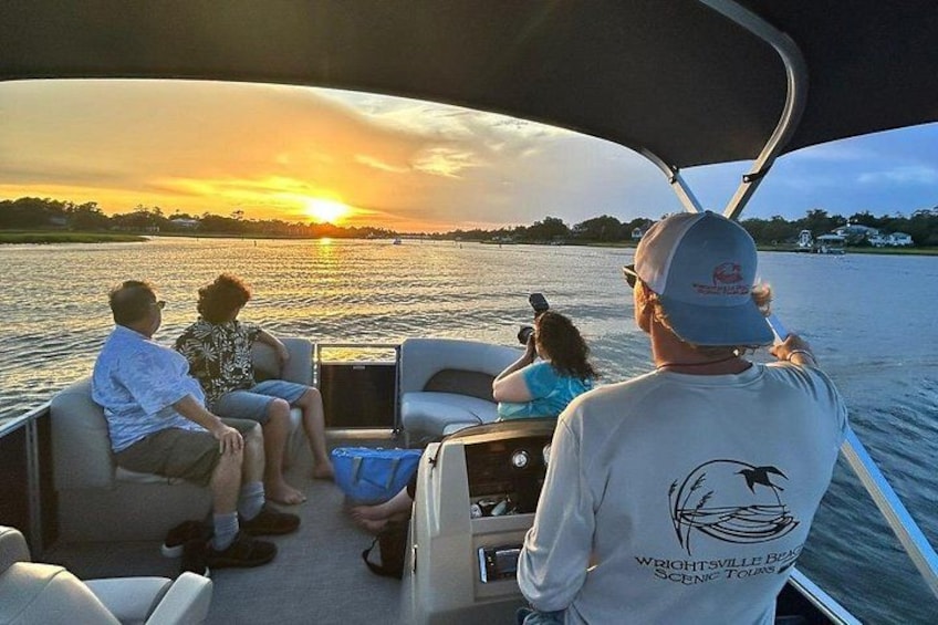 A boat with people enjoying a sunset view. 3
