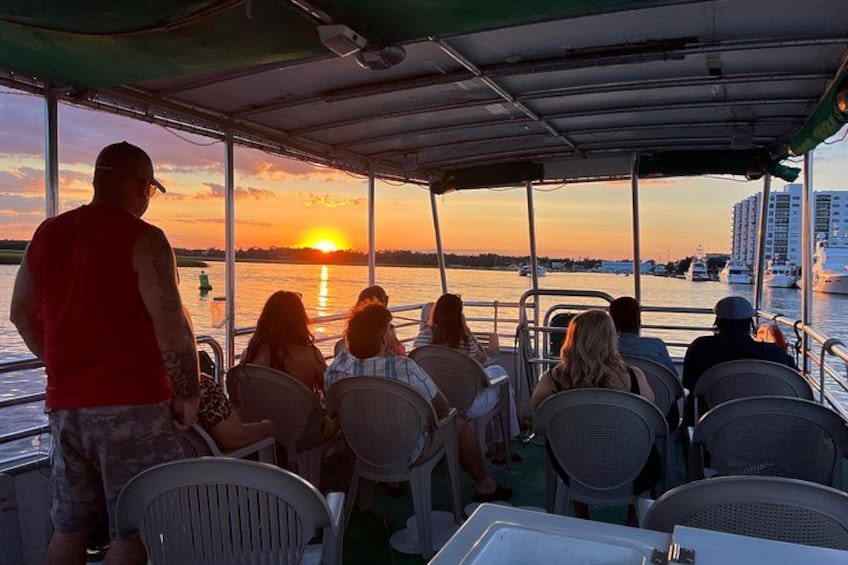 A sunset view from a boat with people seated at tables. 4