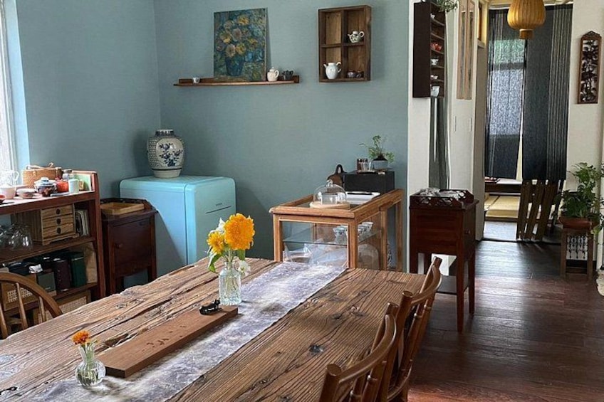 Un tavolo da pranzo in legno con sedie, un vaso con fiori, un frigorifero blu e mensole con oggetti decorativi. 2