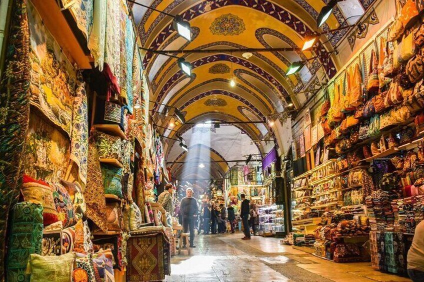 Ein belebter Markt mit bunten Textilien und aufwendigen Mustern an den Wänden. 5