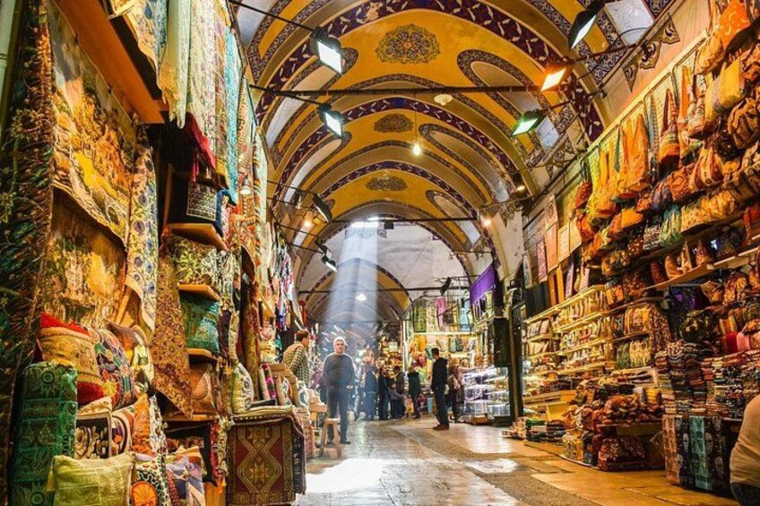 A narrow market with colorful textiles and carpets on display. 5