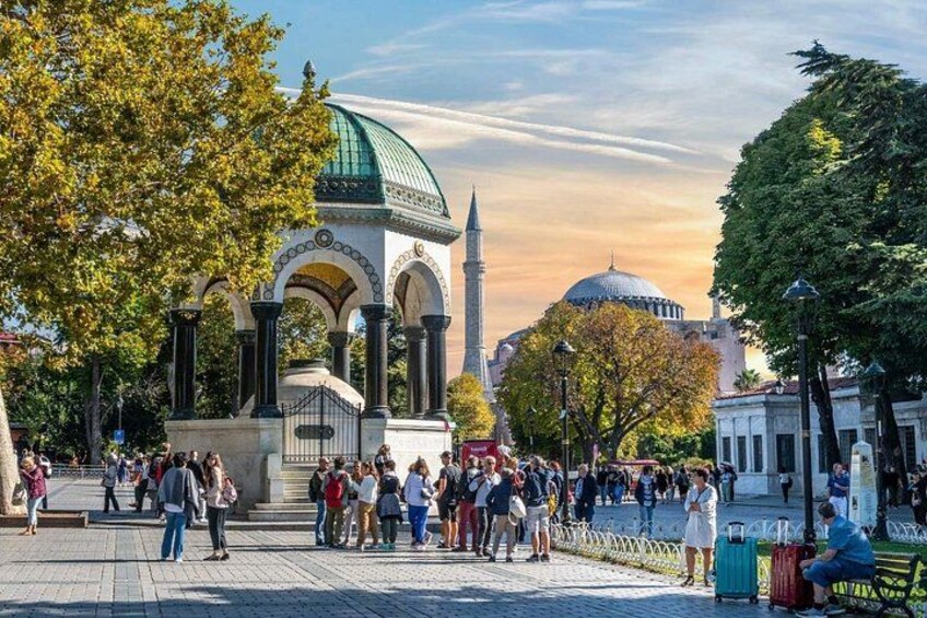 A historical building with a green dome and arches, surrounded by trees and people. 3