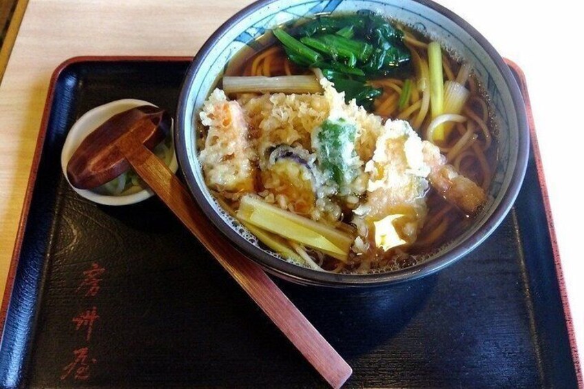 A bowl of ramen with noodles, vegetables, and tofu on a black tray with chopsticks. 3