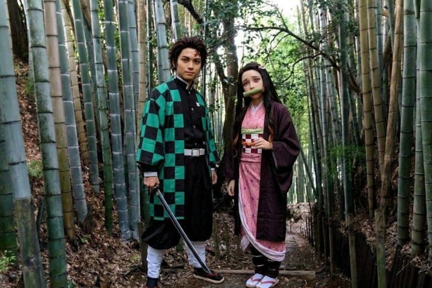 Two people in traditional attire standing in a bamboo forest. 2