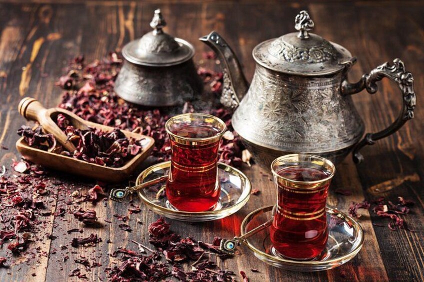 Two cups of tea, a teapot, and a tea strainer on a wooden surface. 4