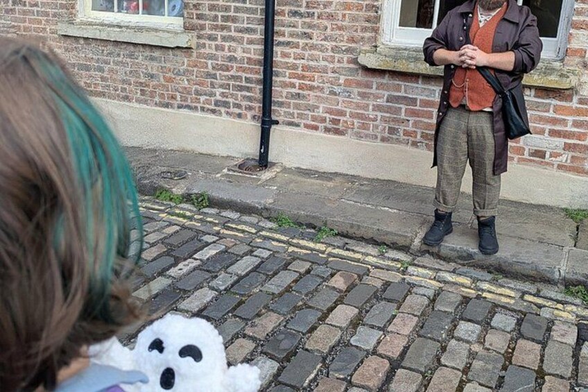 A person standing on a cobblestone street in front of a brick building. 3