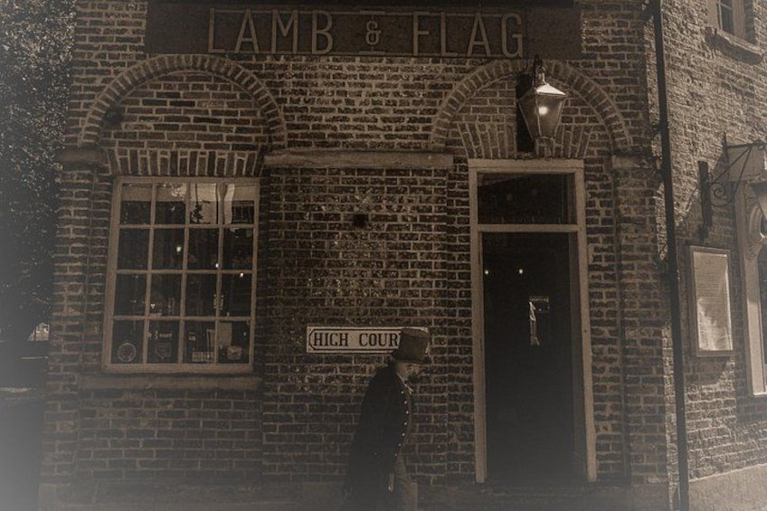A brick building with a sign reading 'LAMB & FLAG' and another sign 'HIGH COURT' below it. 2