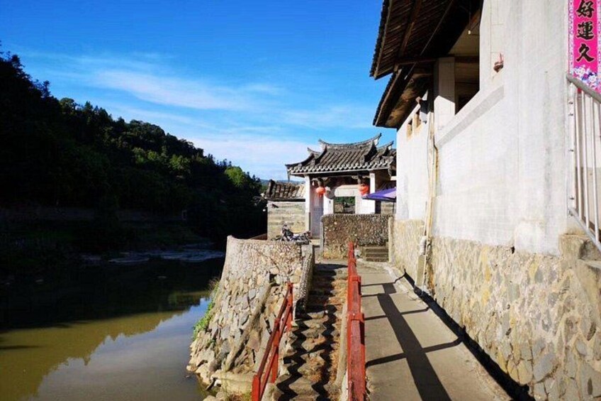 A traditional Chinese building with a stone pathway leading to a water body. 4