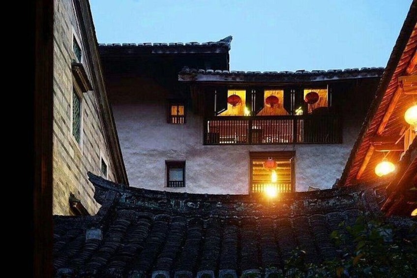 A traditional building with a balcony, a tiled roof, and a lit window. 2