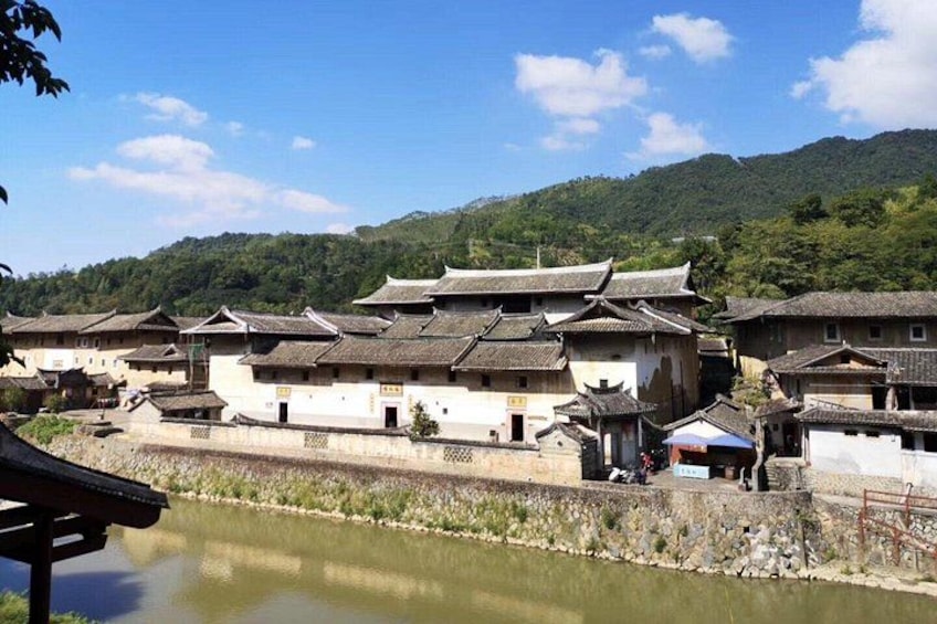 Traditional buildings along a riverbank with a mountainous backdrop. 3