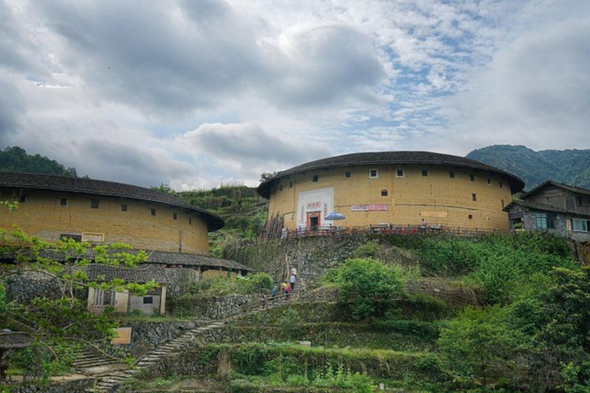 Traditional round buildings with a staircase leading up to them, surrounded by greenery and hills. 5