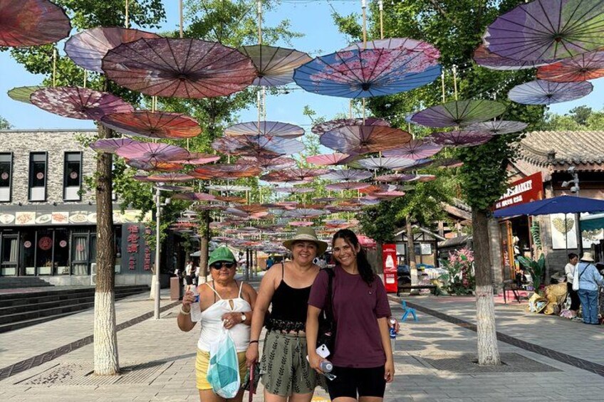 A pedestrian area with colorful umbrellas, trees, and buildings. 4