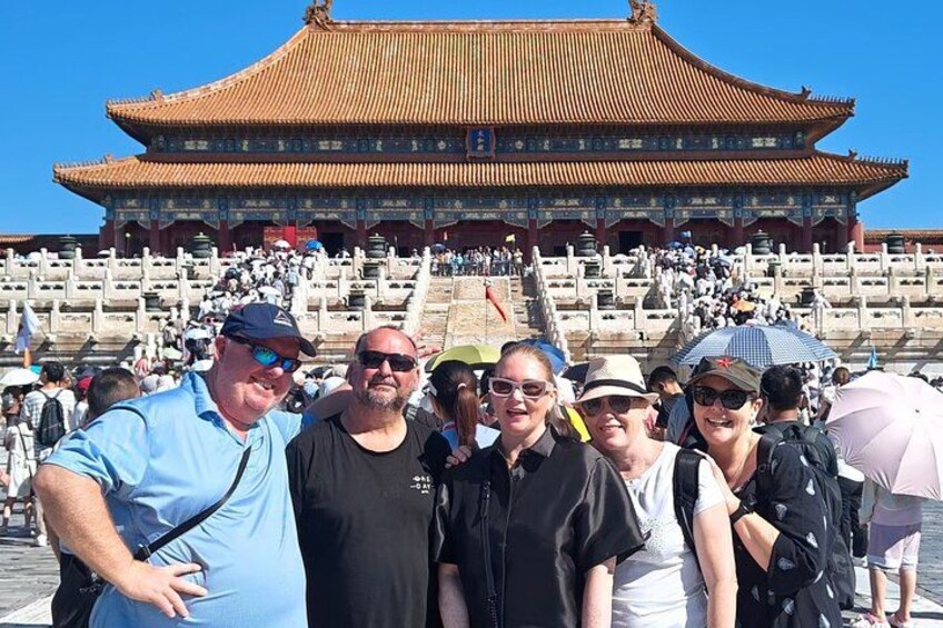 A group of people standing in front of a large, traditional Chinese building with a tiled roof and a staircase leading up to it. 2