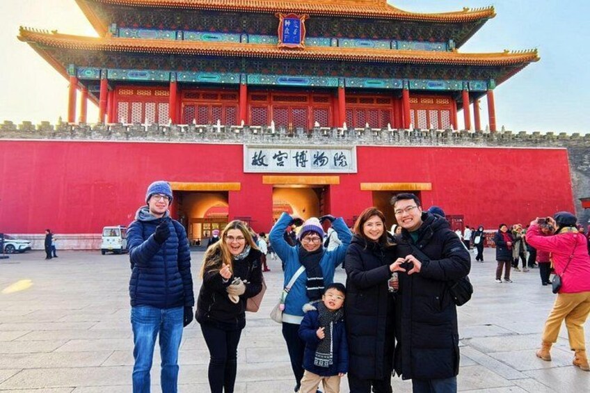 A group of people in front of a traditional building with a red wall and a sign in a foreign language. 5