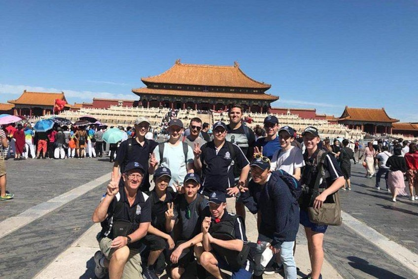 A group of people posing in front of a large traditional building with a tiled roof. 2