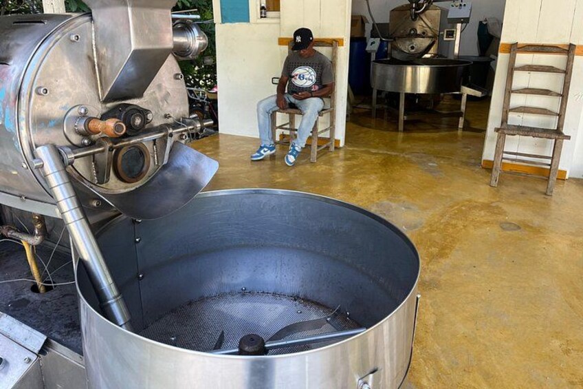 A large industrial machine with a funnel-shaped hopper and a person sitting in the background. 2