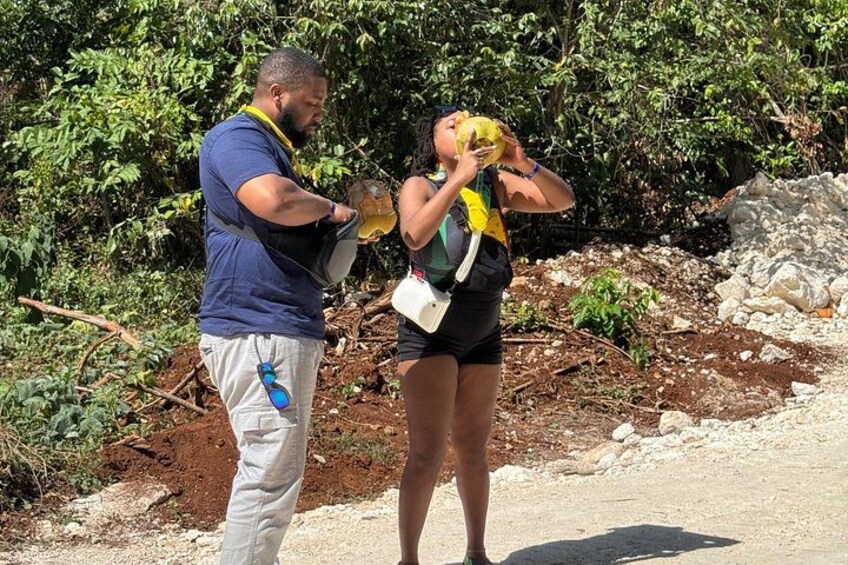 Two people outdoors, one holding a yellow object, standing on a dirt path with vegetation in the background. 4