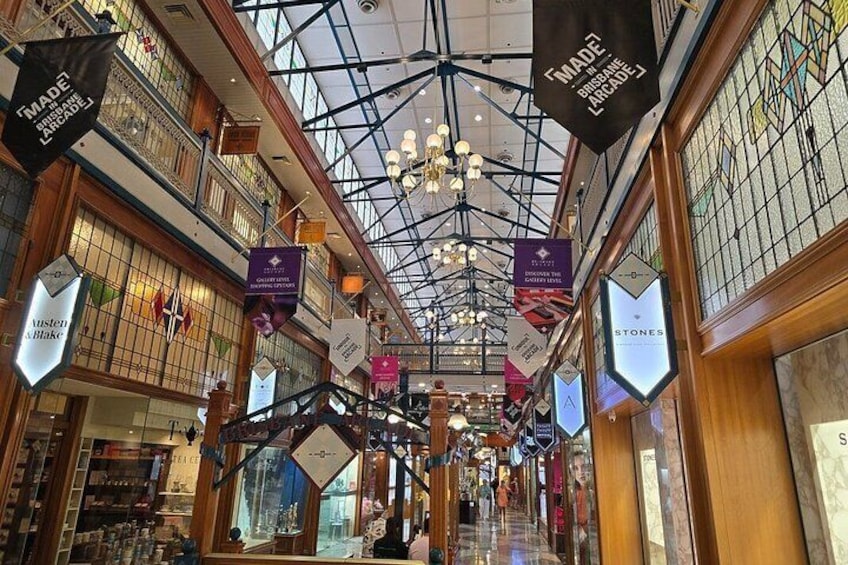 An indoor shopping mall with a high ceiling, glass railings, and hanging banners. 4