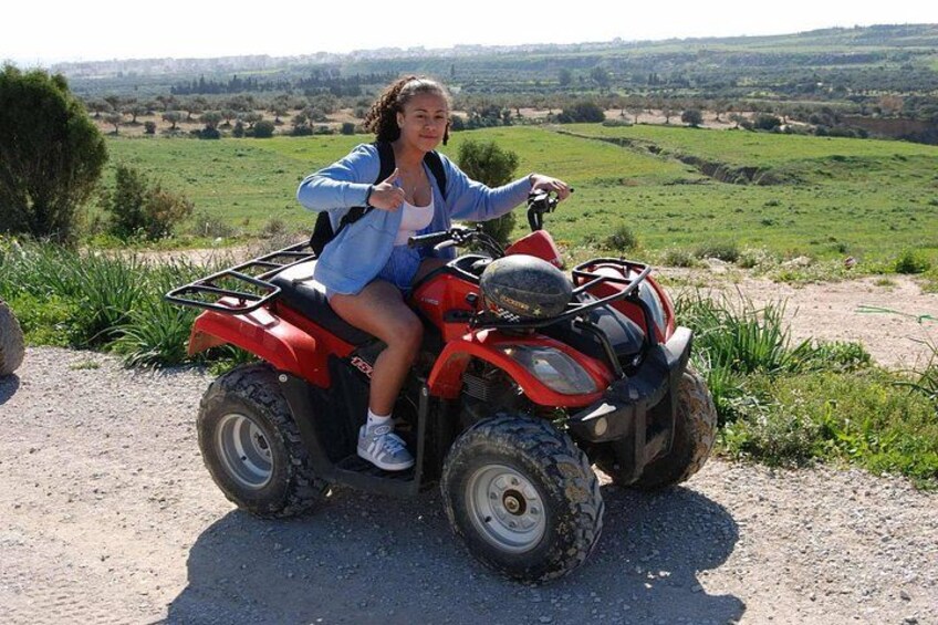 A person riding a red ATV on a dirt path with a rural landscape in the background. 3