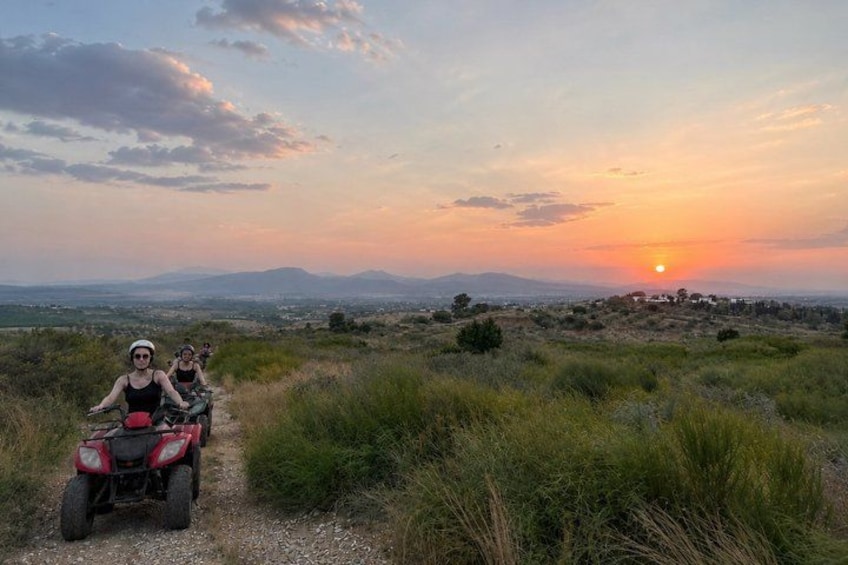 A sunset over a hilly landscape with a dirt path and a quad bike. 5