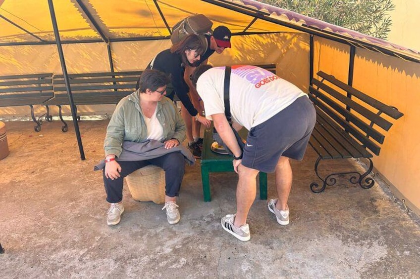 Three people sitting and standing near a bench under a tent. 4