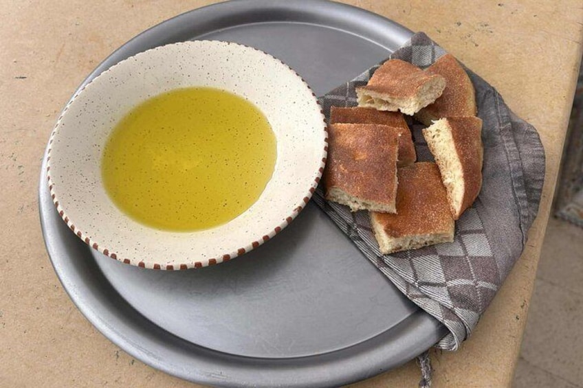 A bowl of olive oil and slices of bread on a gray plate. 3