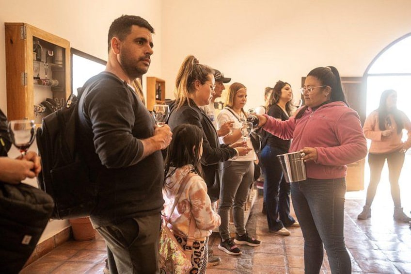 A group of people standing in a room with wooden shelves and a tiled floor. 3