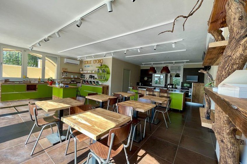 Ein modernes Café mit Holztischen und -stühlen, einer grünen Theke und einer rustikalen Baumstamm-Dekoration. 5