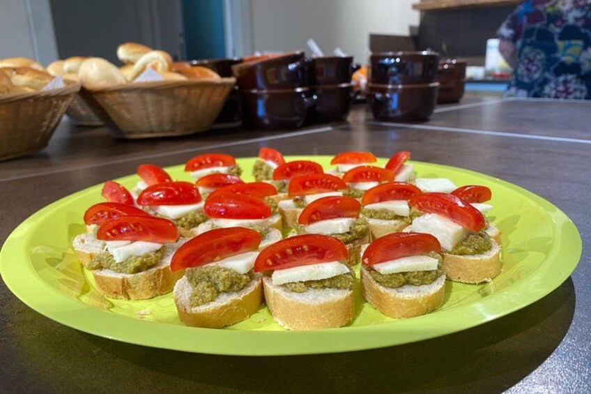 Ein Teller Bruschetta mit Tomaten und Pesto auf einer grünen Schale. 3