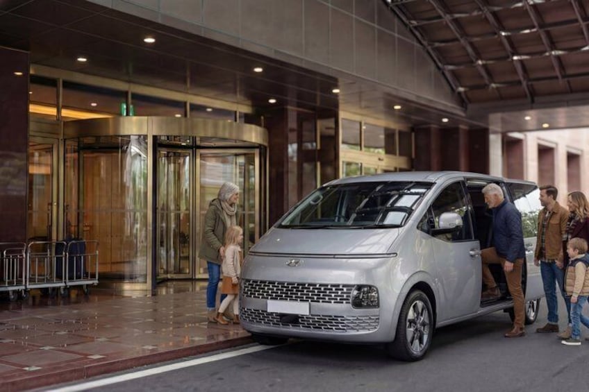 A silver car parked in front of a building with a revolving door. 3