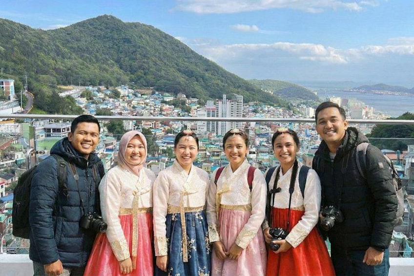 Un grupo de personas en un balcón con vistas a un pueblo costero y montañas al fondo. 2