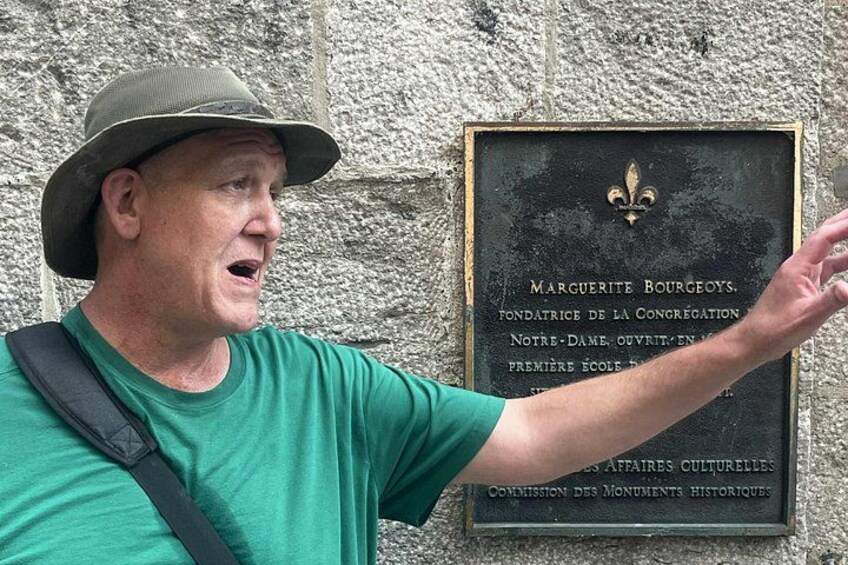A man pointing at a plaque on a stone wall. 3