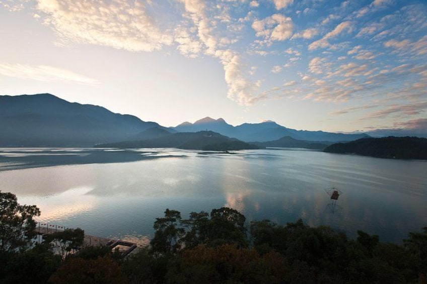 Un lago tranquilo rodeado de montañas, con cielo despejado y algunas nubes. 3