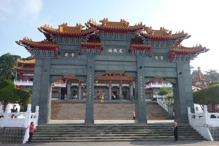 Ein traditionelles chinesisches Tor mit aufwendigen roten und goldenen Dächern, einer zentralen Säule mit Inschriften und einer Treppe, die zum Tor hinaufführt. 3