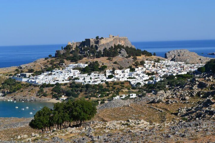 A coastal town with white buildings, a castle on a hill, and the sea in the background. 2