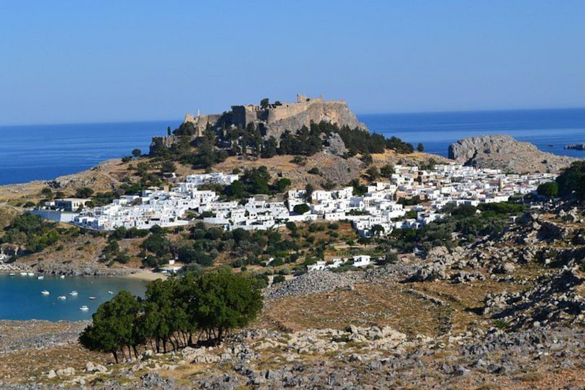 A coastal town with white buildings, a castle on a hill, and the sea in the background. 2