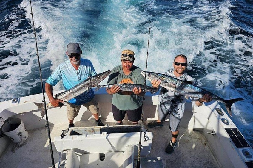 Three people on a boat holding fish. 3