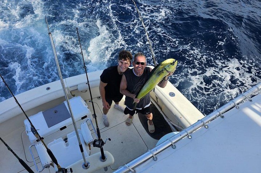 A person holding a fish on a boat with fishing rods and a cooler. 2
