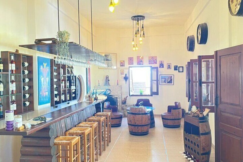 A bar with wooden stools, a counter with bottles, and a wall with framed pictures. 1