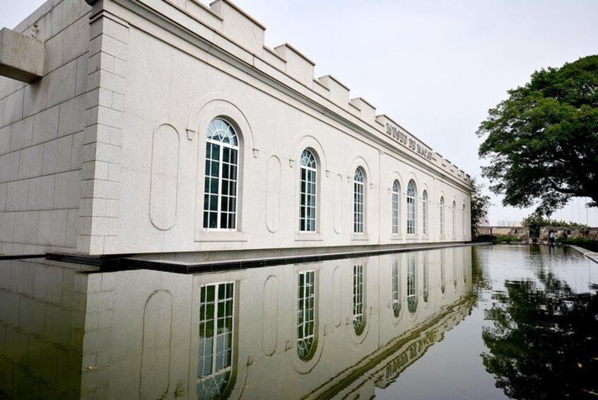 A white building with arched windows reflecting on water. 2