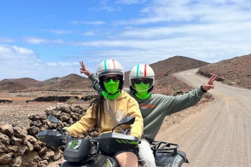 Dos personas en un camino de tierra con terreno rocoso y colinas al fondo. 3