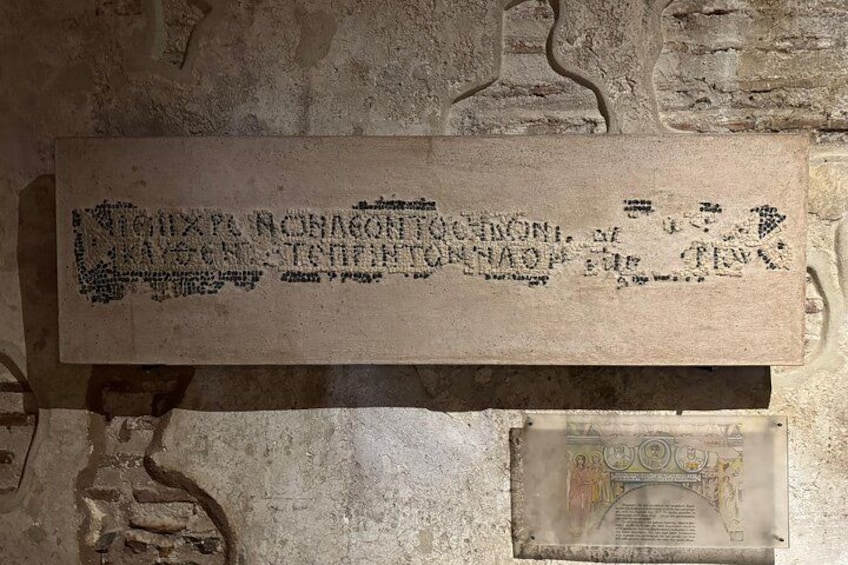 Une plaque de pierre ornée d’inscriptions gravées et, en dessous, un document plus petit, partiellement visible. 3